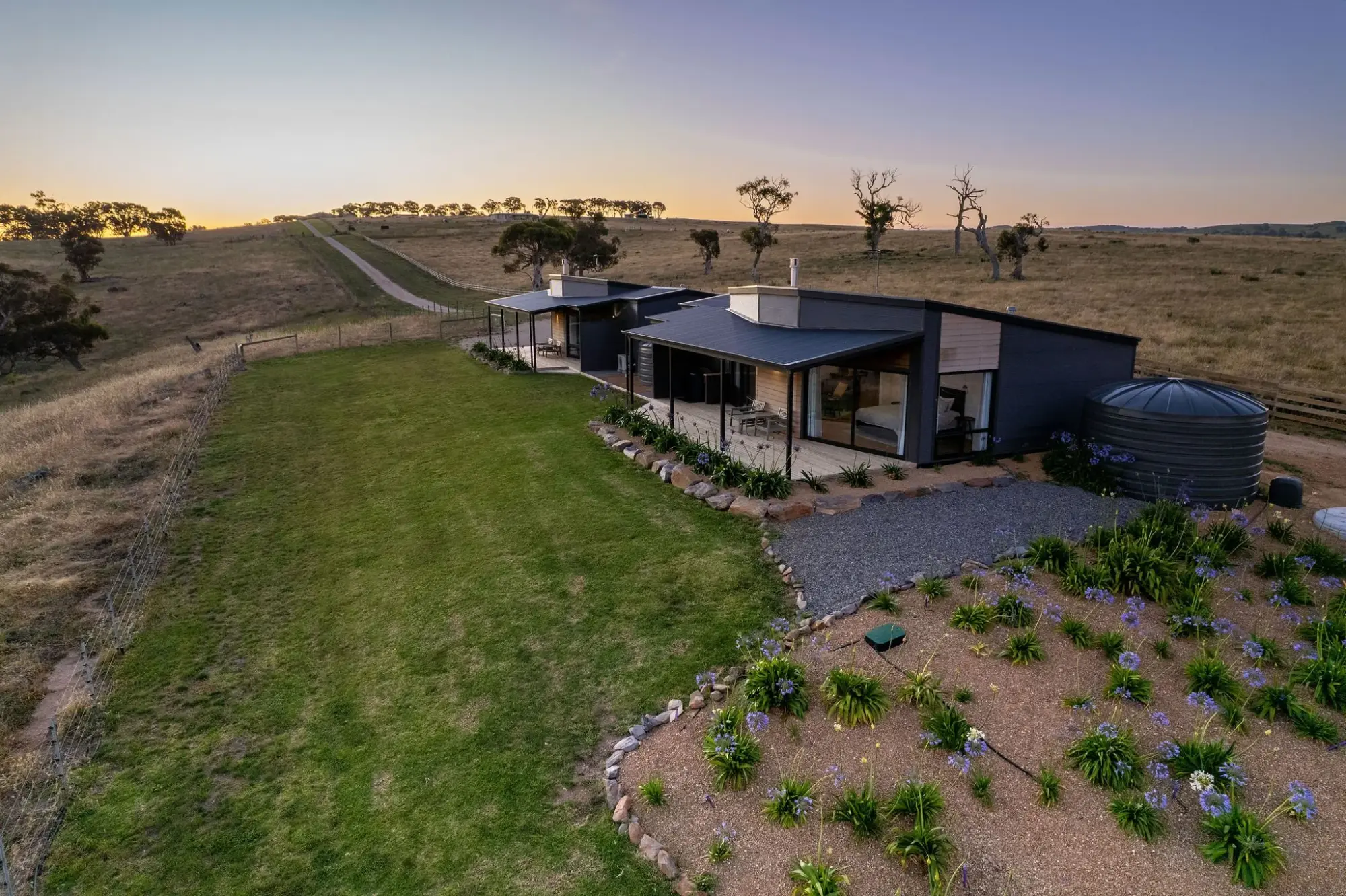 The villas from the rise at golden hour, the gravel drive curving in past young plantings.