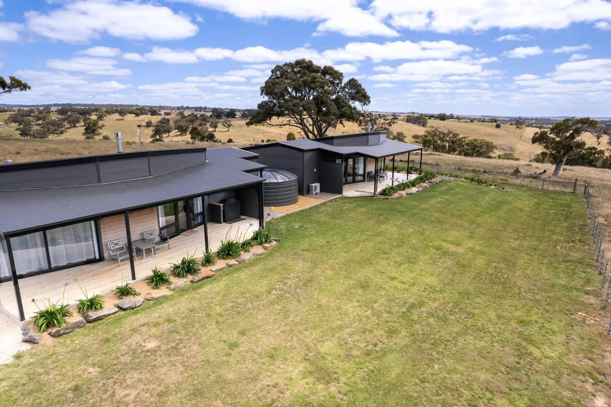 A villa seen across the lawn on a clear day, gum trees along the boundary.