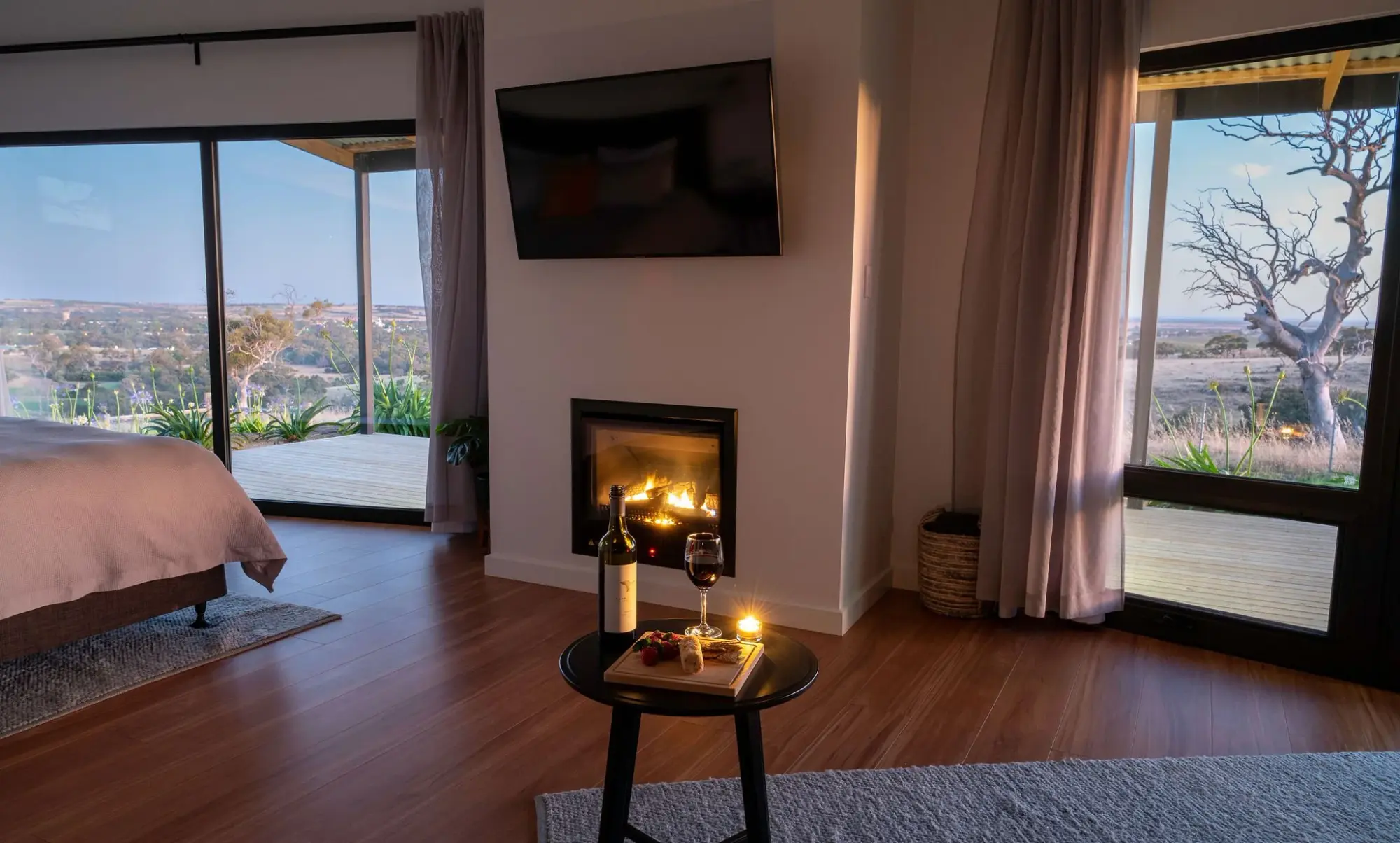 Inside a villa after dark, the gas fire lit and candles on the table, with the valley through the glass.